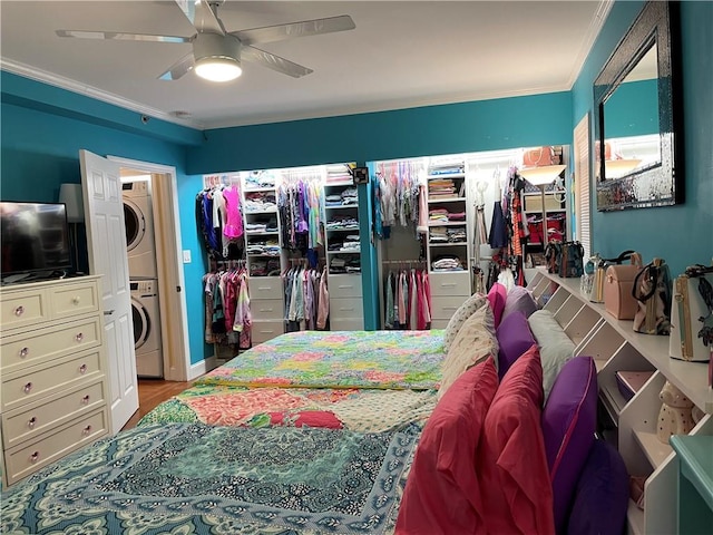 bedroom with crown molding, ceiling fan, and stacked washer / drying machine