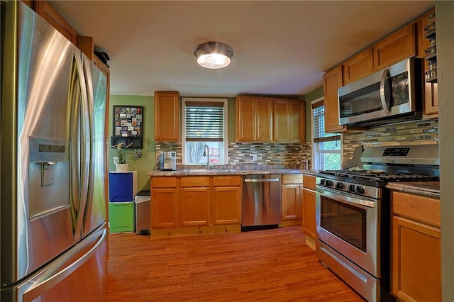 kitchen with tasteful backsplash, appliances with stainless steel finishes, light hardwood / wood-style floors, and a wealth of natural light