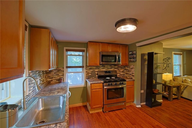 kitchen with light wood-type flooring, appliances with stainless steel finishes, backsplash, and sink