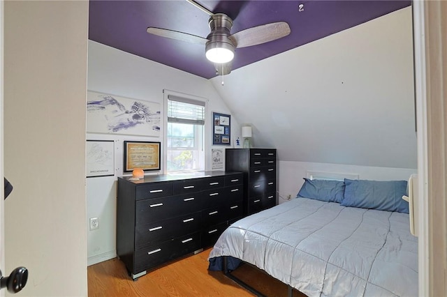 bedroom featuring ceiling fan, light hardwood / wood-style floors, and lofted ceiling