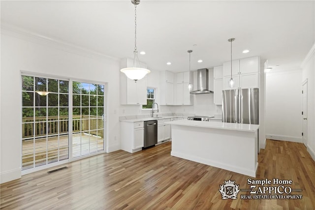 kitchen with a center island, stainless steel appliances, white cabinetry, and wall chimney range hood