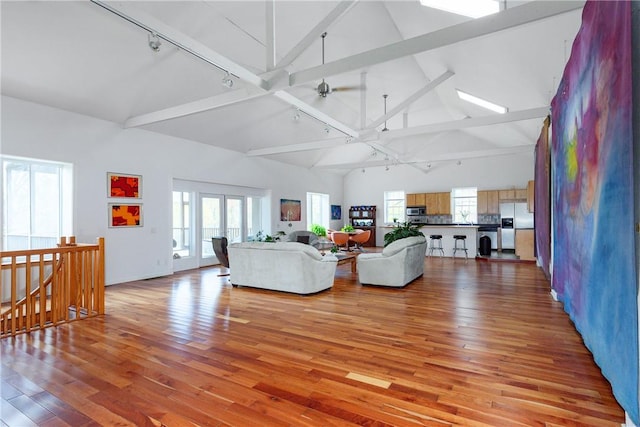 living room featuring track lighting, a healthy amount of sunlight, high vaulted ceiling, and light hardwood / wood-style flooring