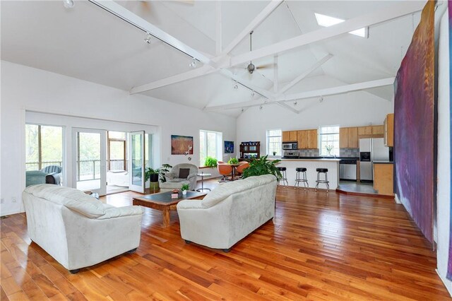 living room with beamed ceiling, high vaulted ceiling, and light hardwood / wood-style flooring