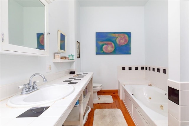 bathroom with a tub, vanity, wood-type flooring, and toilet