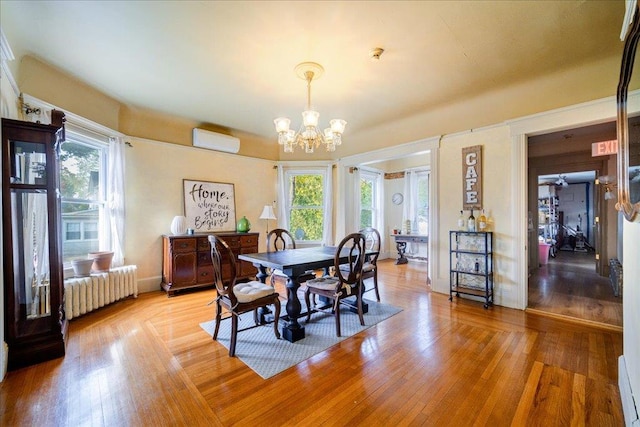 dining room with an AC wall unit, radiator heating unit, light hardwood / wood-style floors, and an inviting chandelier