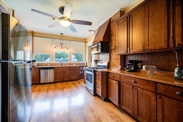 kitchen featuring pendant lighting, ceiling fan, light wood-type flooring, appliances with stainless steel finishes, and tasteful backsplash