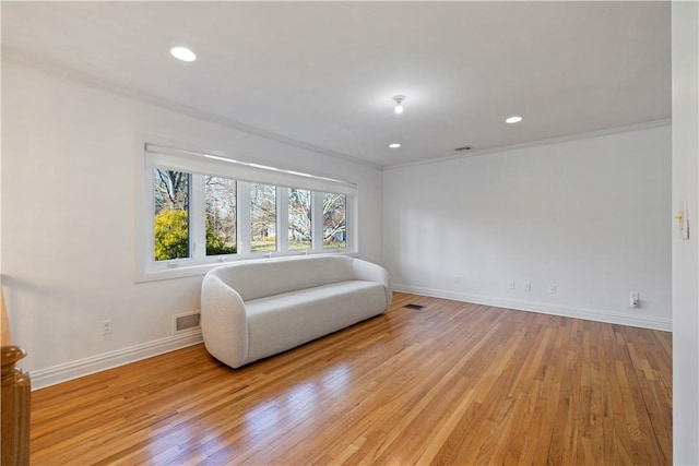 living area featuring light wood-type flooring and ornamental molding