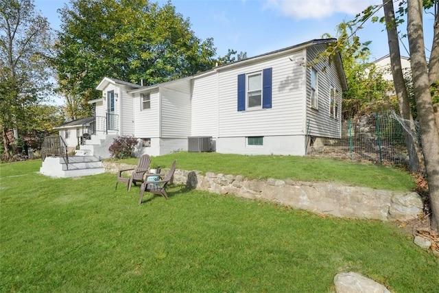 rear view of property featuring central AC and a yard