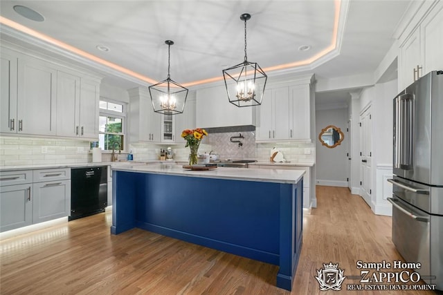 kitchen featuring a center island, white cabinets, light wood-type flooring, appliances with stainless steel finishes, and decorative light fixtures