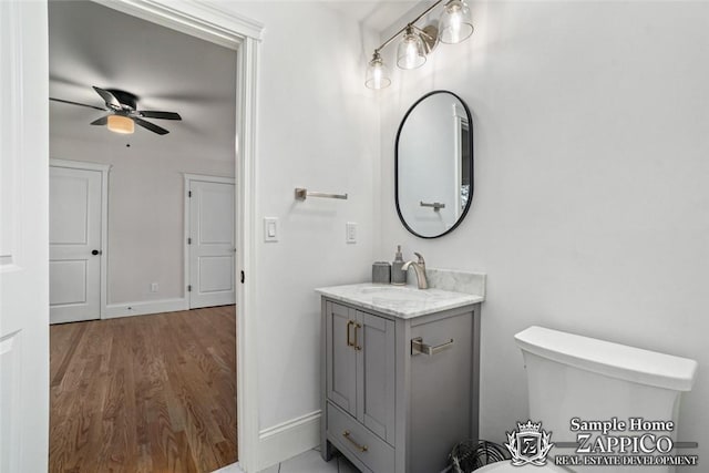 bathroom with hardwood / wood-style floors, vanity, toilet, and ceiling fan