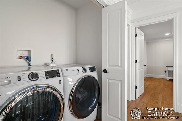 washroom featuring washing machine and clothes dryer, crown molding, and light hardwood / wood-style flooring