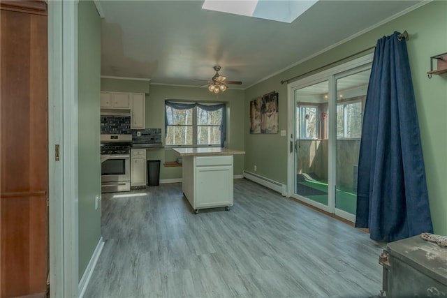 kitchen featuring a skylight, white cabinetry, baseboard heating, stainless steel range oven, and decorative backsplash