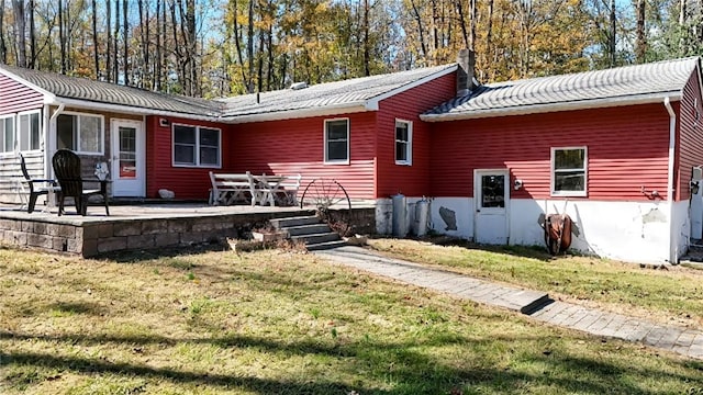 rear view of property featuring a lawn, a patio area, and a sunroom