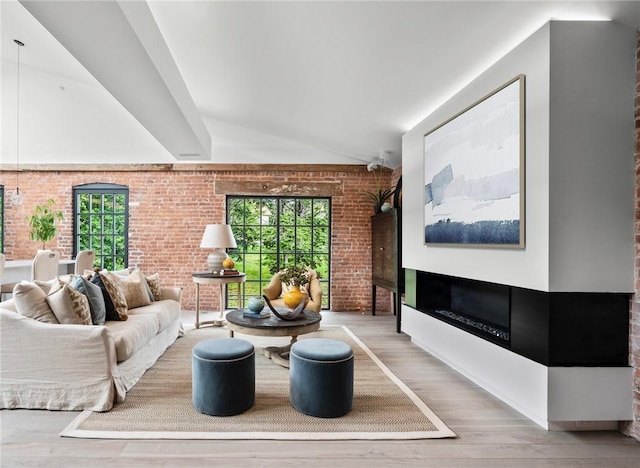 living room with hardwood / wood-style flooring, vaulted ceiling with beams, and brick wall