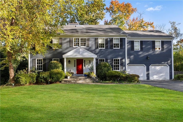 colonial-style house with a garage, aphalt driveway, and a front lawn