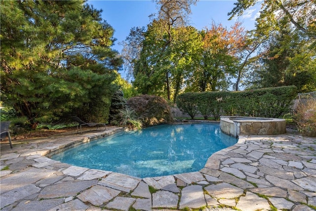 view of pool featuring a patio, fence, and a pool with connected hot tub