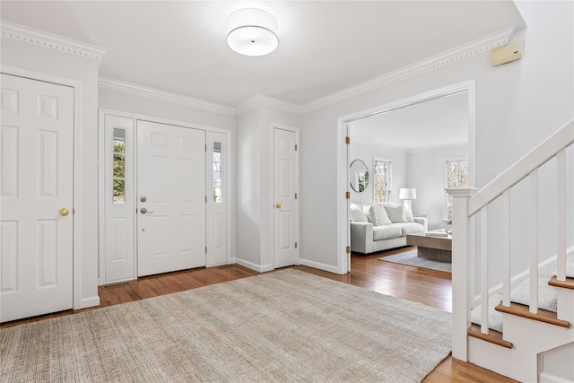 foyer entrance featuring stairs, ornamental molding, wood finished floors, and baseboards