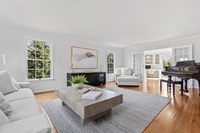 living area with ornamental molding, light wood-style flooring, and baseboards