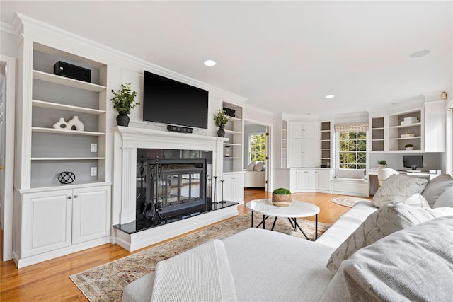 living room with ornamental molding, a tile fireplace, light wood-style flooring, and recessed lighting