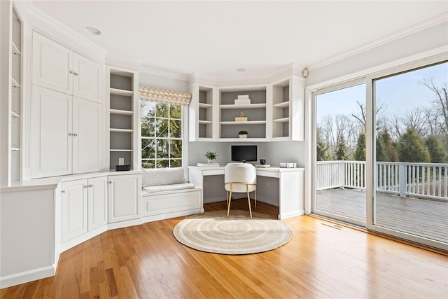 unfurnished office with ornamental molding, built in study area, light wood-style flooring, and a healthy amount of sunlight