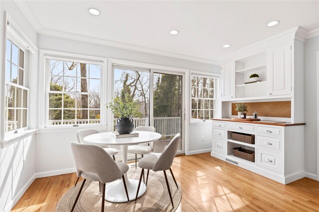 dining space featuring baseboards, light wood finished floors, plenty of natural light, and crown molding