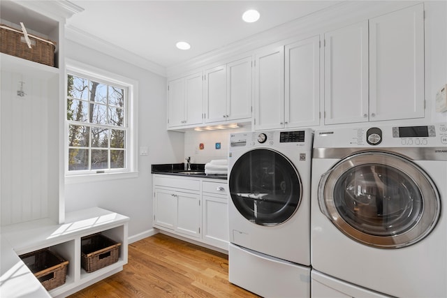 laundry room featuring washing machine and clothes dryer, recessed lighting, cabinet space, light wood-style floors, and ornamental molding