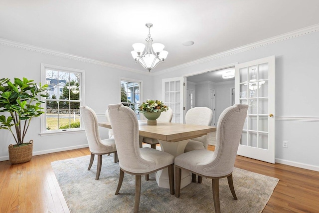 dining space with an inviting chandelier, baseboards, ornamental molding, and wood finished floors