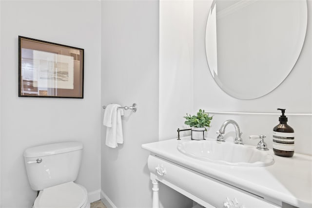 half bathroom with toilet, vanity, and baseboards