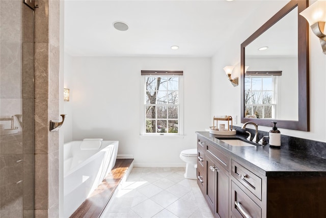 full bath featuring a washtub, toilet, vanity, baseboards, and tile patterned floors