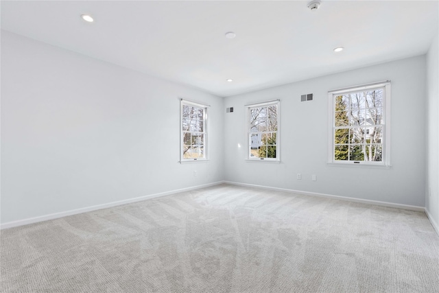 carpeted empty room with plenty of natural light, visible vents, baseboards, and recessed lighting