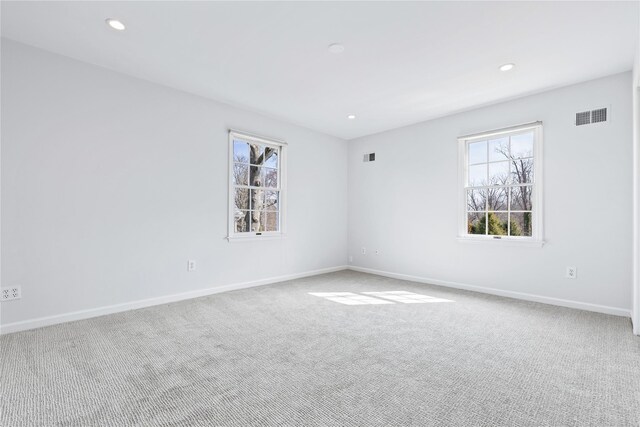 unfurnished room with a healthy amount of sunlight, carpet floors, and visible vents