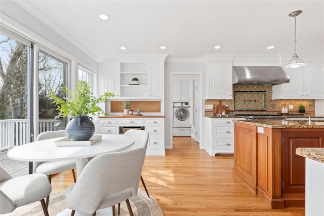 kitchen with light wood-type flooring, washer / dryer, range hood, and ornamental molding