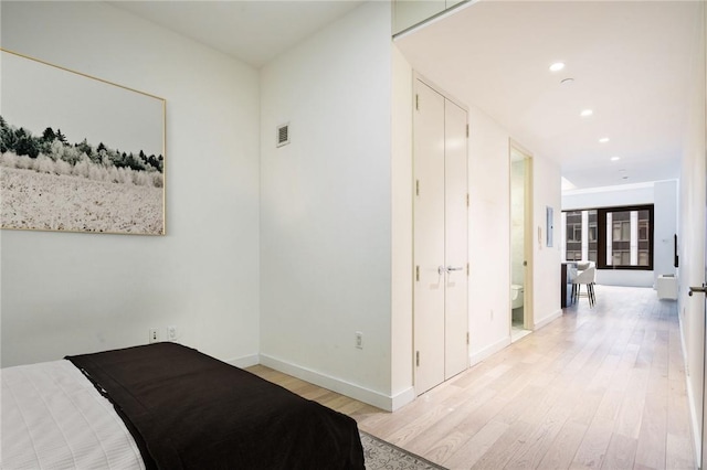 bedroom featuring connected bathroom, light hardwood / wood-style flooring, and french doors