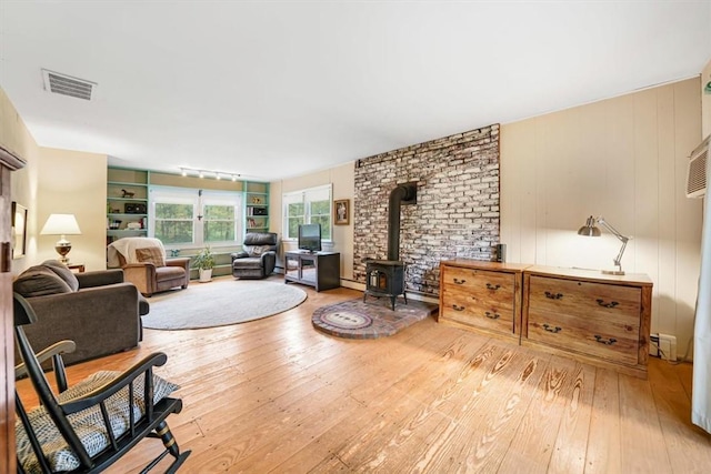 living room with hardwood / wood-style flooring, wood walls, a wood stove, and a baseboard heating unit