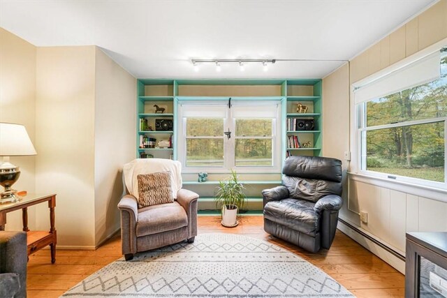 living area featuring light wood-type flooring, baseboard heating, and track lighting