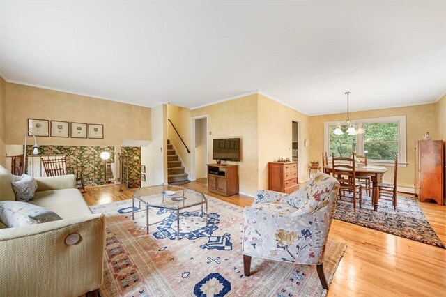 living room with crown molding, light hardwood / wood-style floors, a baseboard radiator, and a notable chandelier