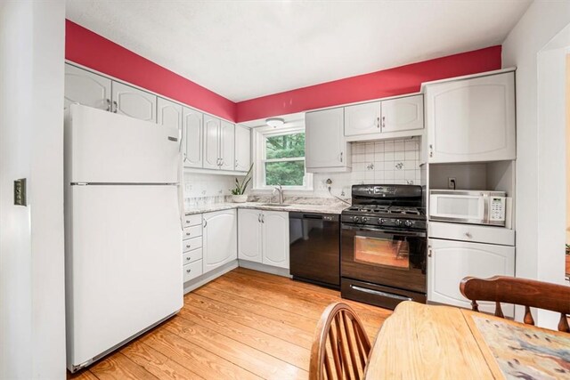 kitchen with light wood-type flooring, backsplash, sink, black appliances, and white cabinets