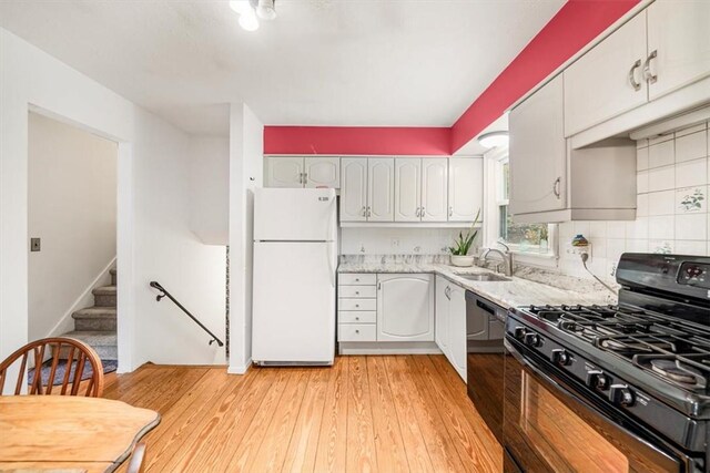 kitchen with sink, backsplash, light hardwood / wood-style floors, white cabinets, and black appliances