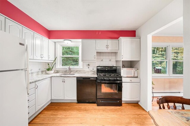 kitchen featuring black appliances, sink, light wood-type flooring, tasteful backsplash, and white cabinetry