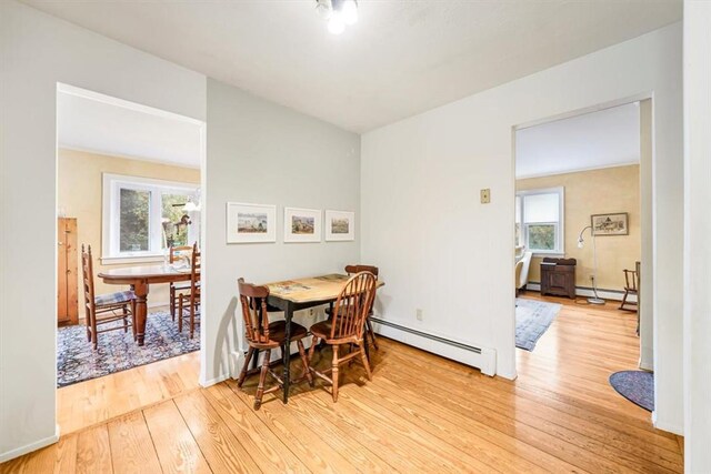 dining area featuring a healthy amount of sunlight, light wood-type flooring, and a baseboard heating unit