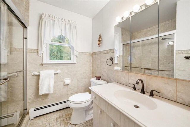 bathroom with walk in shower, vanity, a baseboard heating unit, tile walls, and toilet