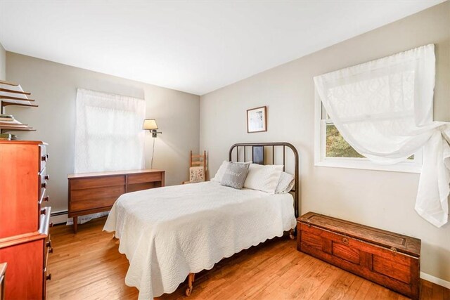 bedroom with baseboard heating and light hardwood / wood-style flooring