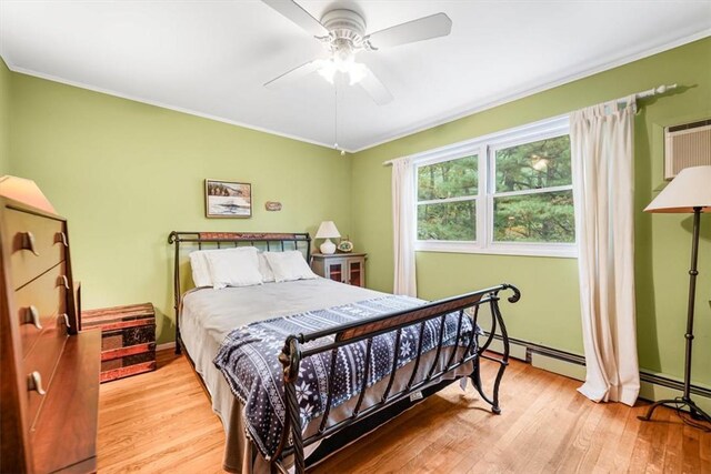 bedroom featuring a baseboard heating unit, light hardwood / wood-style floors, ceiling fan, and crown molding