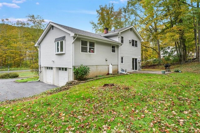 back of house featuring a garage and a yard