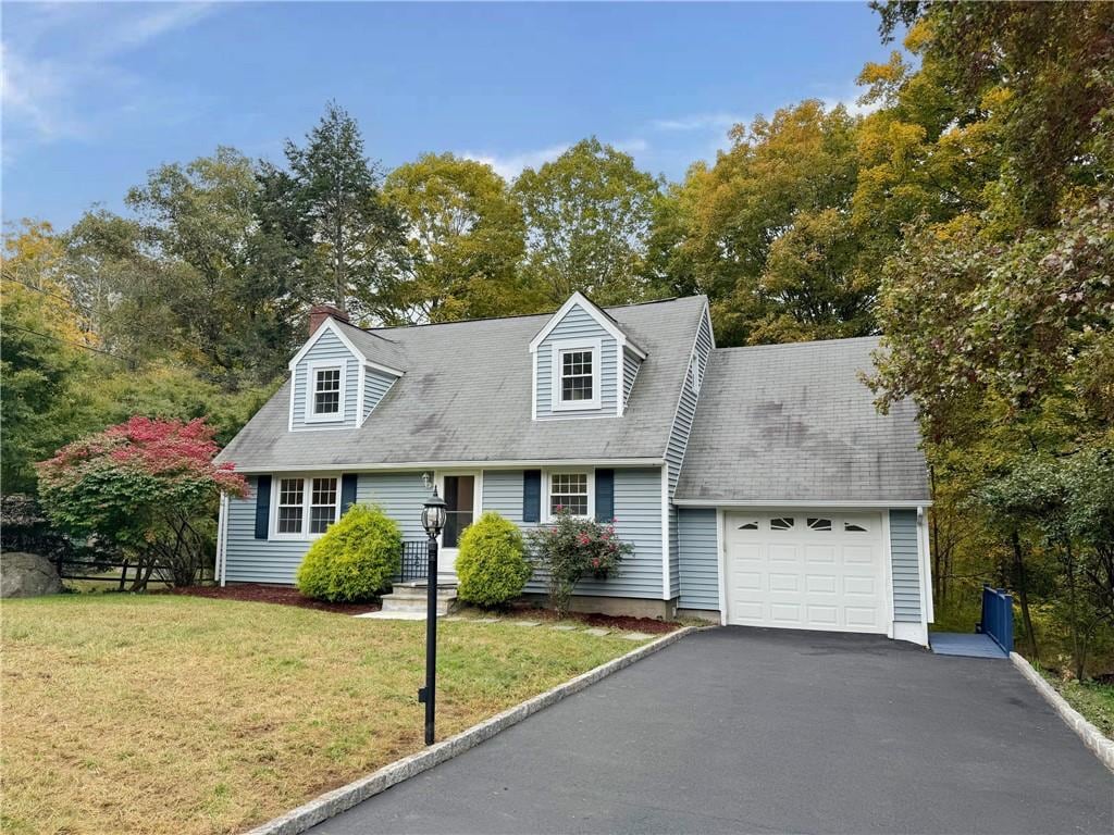 cape cod home with a garage and a front lawn