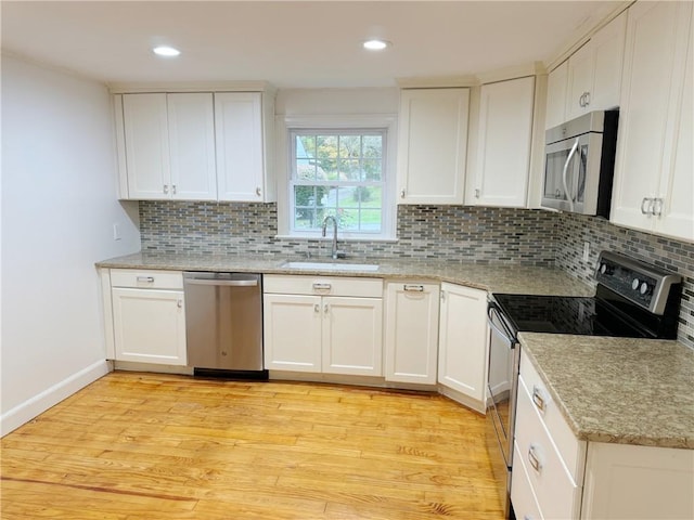 kitchen with sink, tasteful backsplash, light hardwood / wood-style floors, white cabinetry, and stainless steel appliances