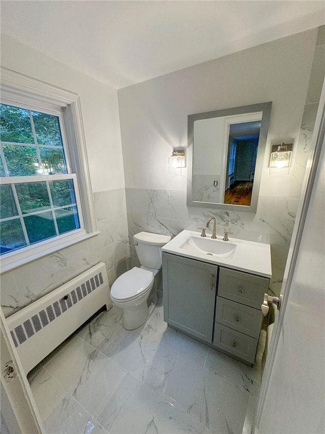 bathroom featuring vanity, toilet, tile walls, and radiator