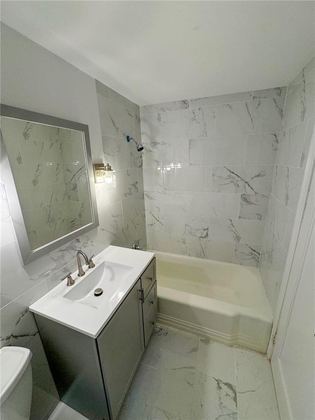 full bathroom with vanity, tiled shower / bath combo, toilet, and tile walls