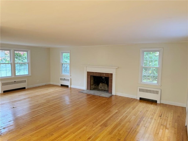 unfurnished living room with a wealth of natural light, light wood-type flooring, and radiator