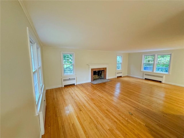 unfurnished living room featuring crown molding, light wood-type flooring, radiator heating unit, and a fireplace